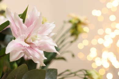 Photo of Beautiful lily flower against beige background with blurred lights, closeup. Space for text