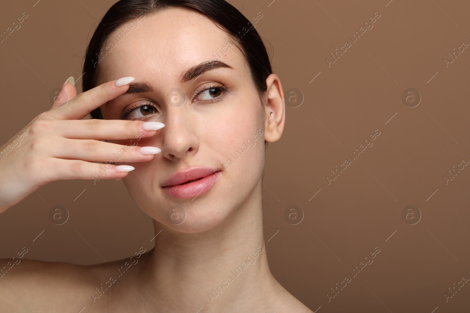 Photo of Portrait of beautiful young woman on brown background. Space for text