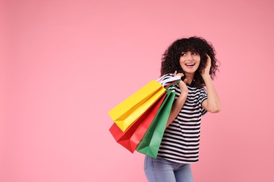 Photo of Happy young woman with shopping bags on pink background. Space for text