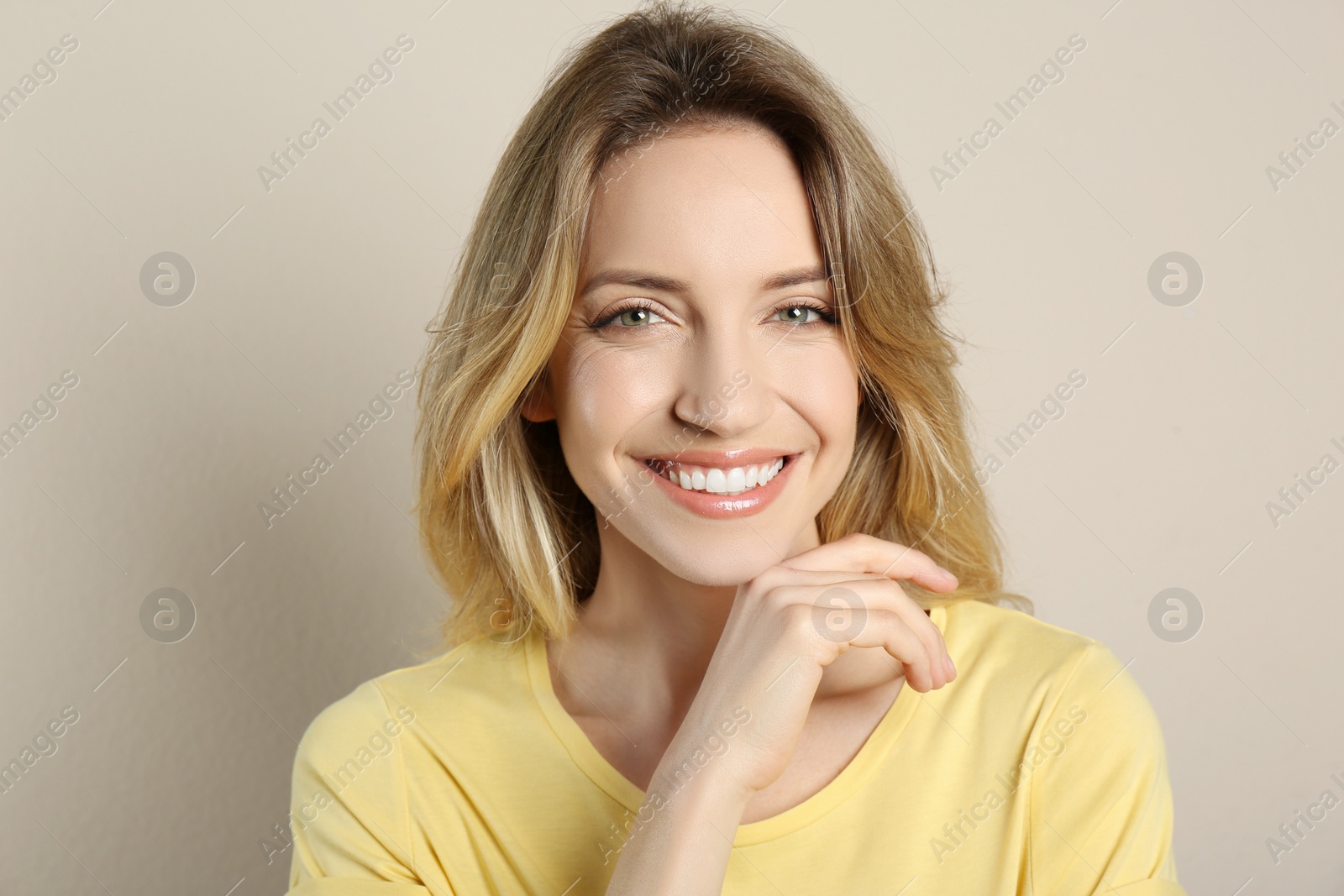 Photo of Portrait of happy young woman with beautiful blonde hair and charming smile on beige background