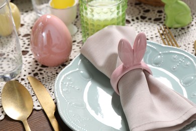 Photo of Festive table setting with napkin ring in shape of bunny ears, closeup. Easter celebration