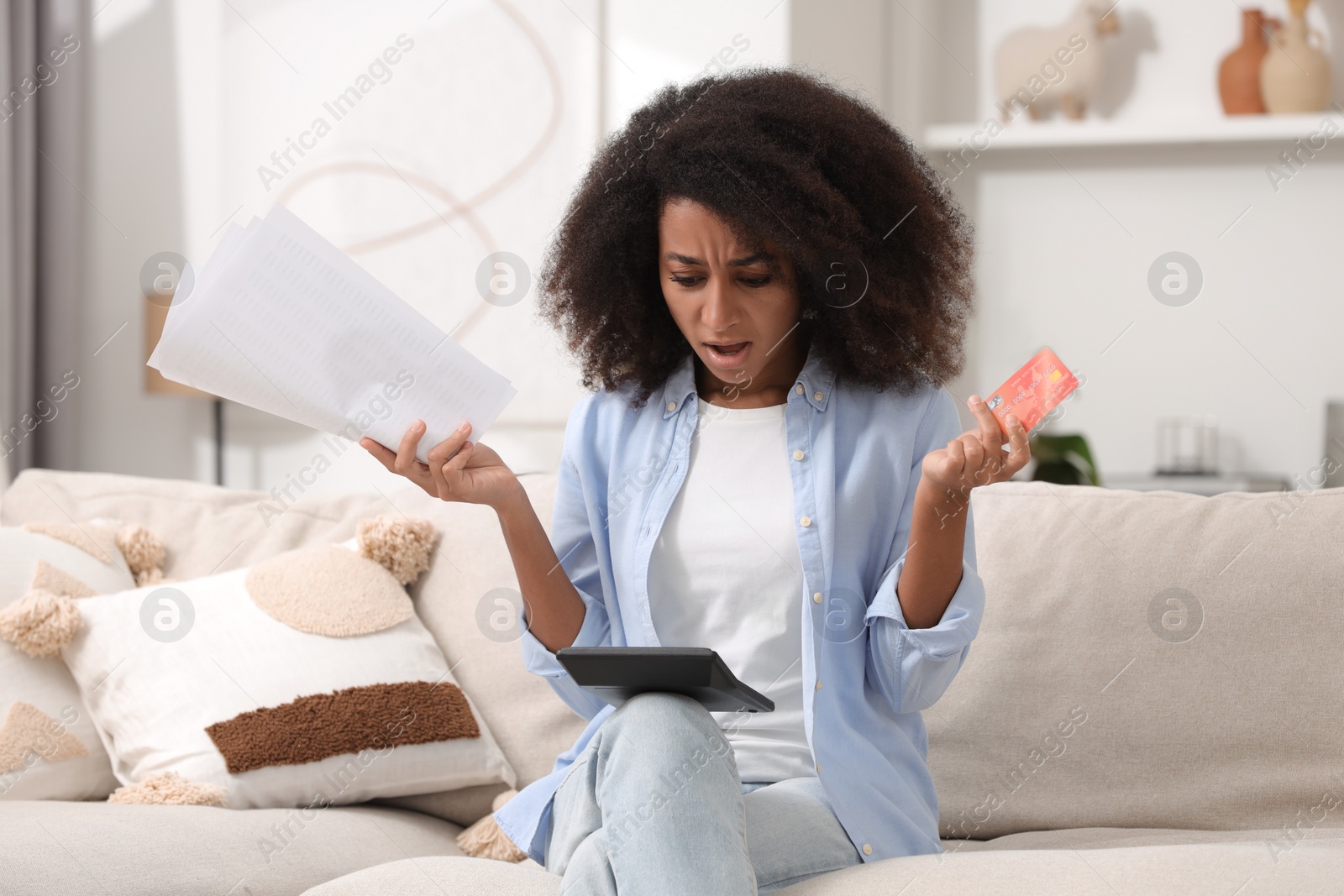 Photo of Shocked woman with calculator and credit card planning budget at home. Debt problem