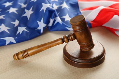 Judge's gavel and American flag on light wooden table