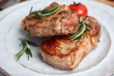 Photo of Delicious fried meat with rosemary and tomato on plate, closeup