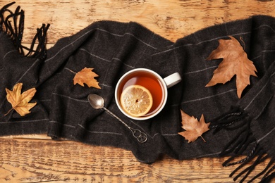 Flat lay composition with hot cozy drink, scarf and autumn leaves on wooden background