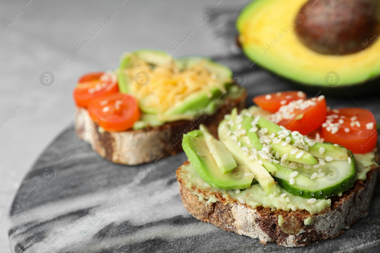 Photo of Delicious avocado sandwiches on marble board, closeup