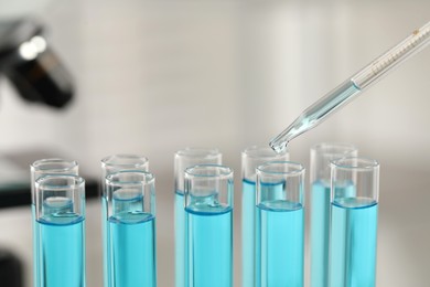 Photo of Dripping liquid from pipette into test tube in laboratory, closeup