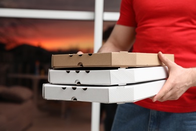 Photo of Courier with pizza boxes on blurred background, closeup