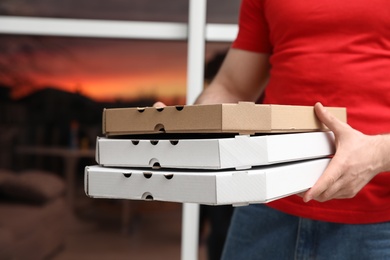 Courier with pizza boxes on blurred background, closeup