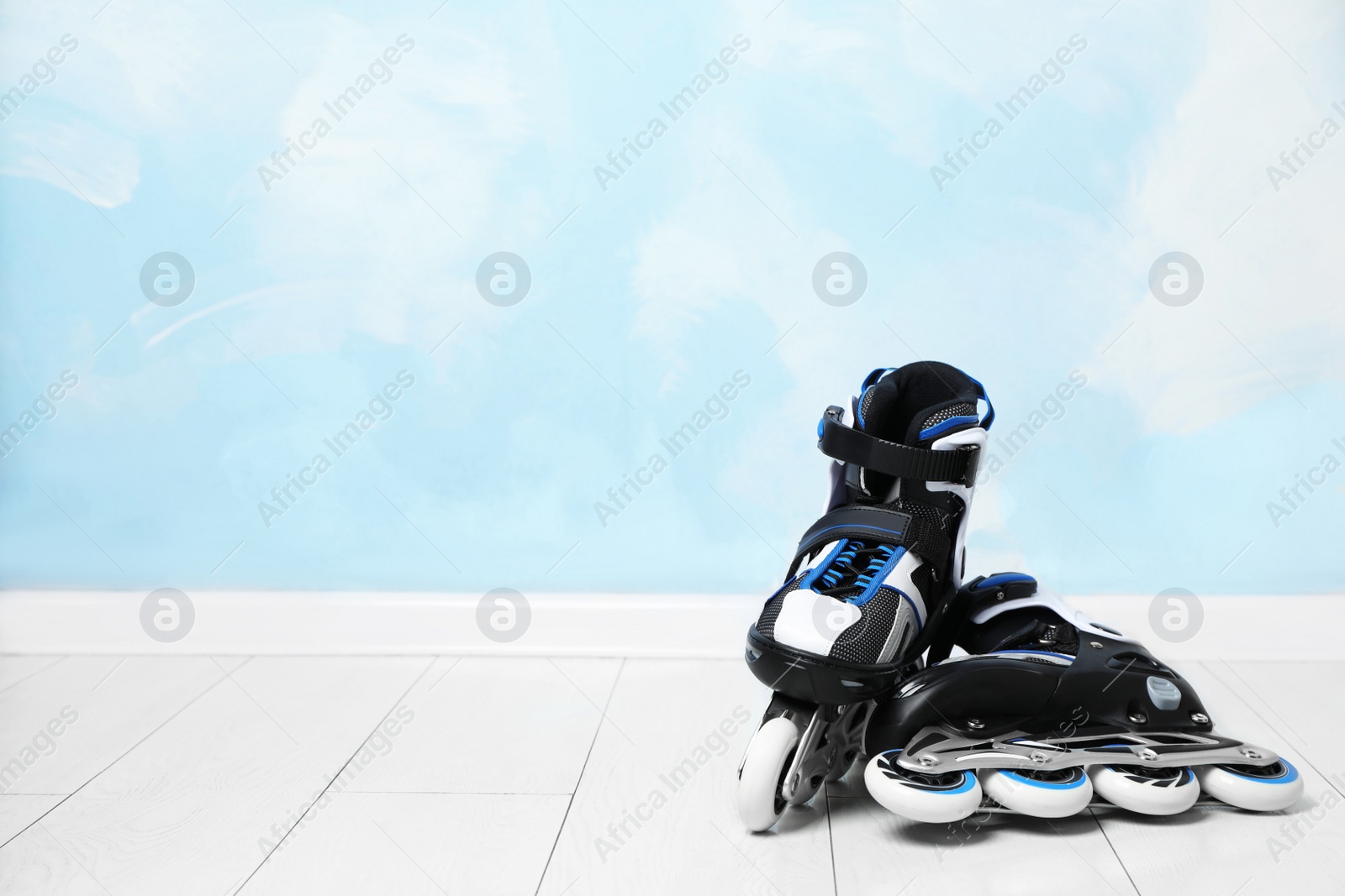 Photo of Inline roller skates on floor near color wall. Space for text