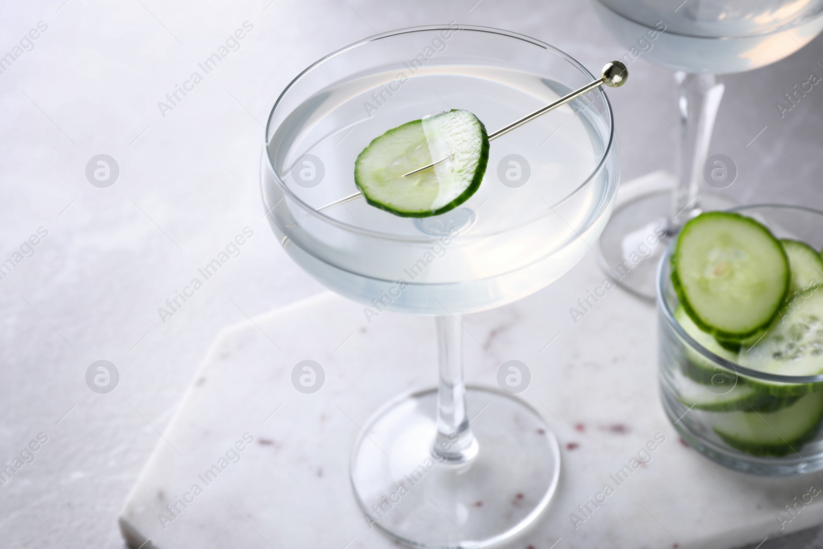 Photo of Glass of martini with cucumber on light table. Space for text