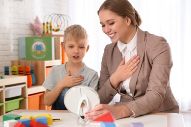 Speech therapist working with little boy in office