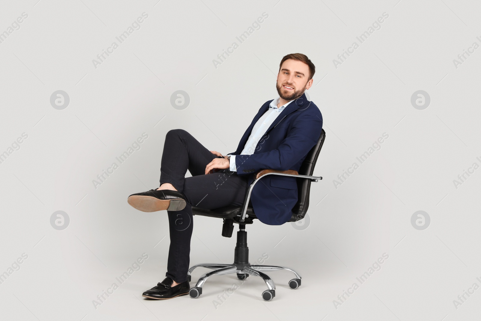 Photo of Young businessman sitting in comfortable office chair on grey background