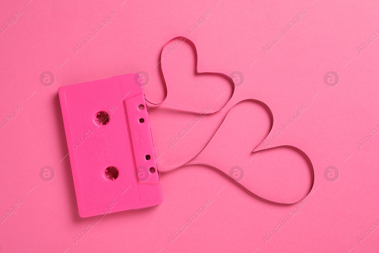 Photo of Music cassette and hearts made with tape on pink background, top view. Listening love song