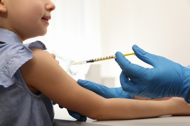 Doctor giving injection to little girl in hospital, closeup. Immunization concept