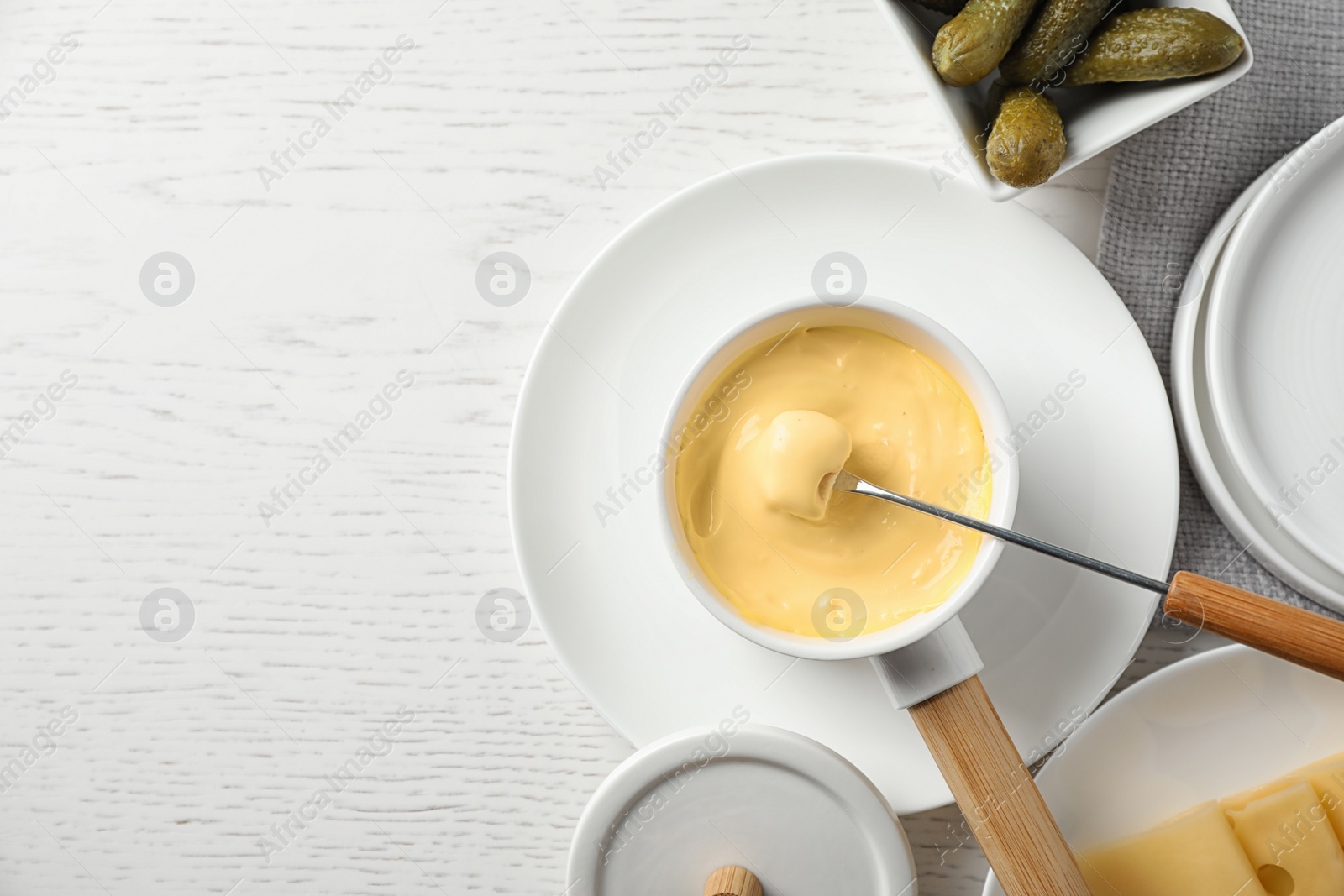 Photo of Flat lay composition with pot of tasty cheese fondue on white wooden table, space for text