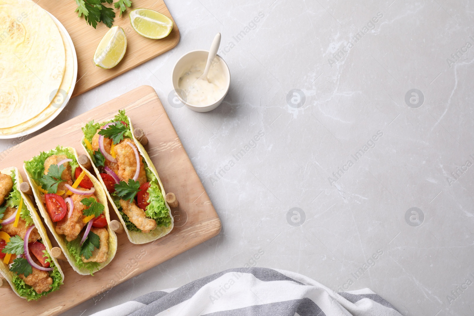 Photo of Yummy fish tacos served on marble table, flat lay. Space for text