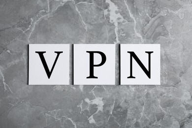 Photo of Paper notes with acronym VPN on light grey marble table, flat lay