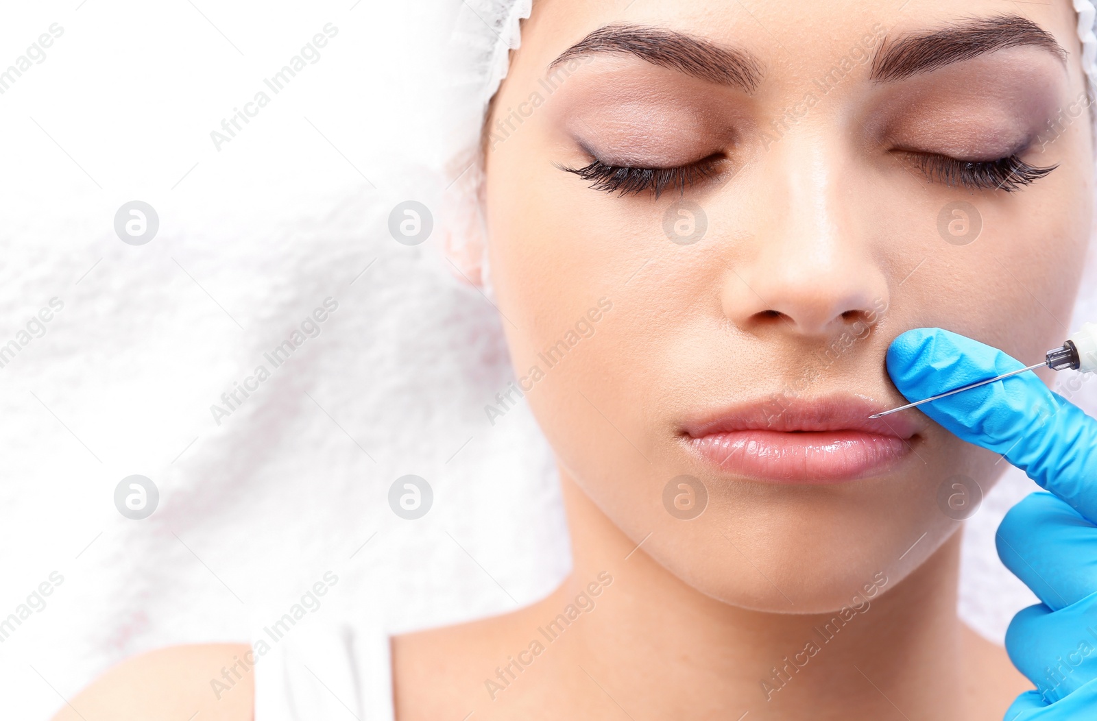 Photo of Young woman getting lip injection in beautician salon, closeup