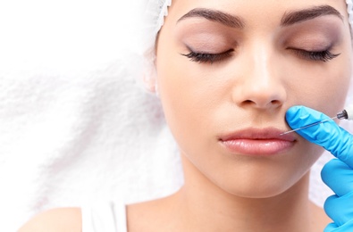 Photo of Young woman getting lip injection in beautician salon, closeup