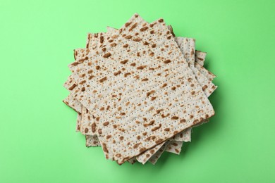 Photo of Stack of traditional matzos on green background, top view