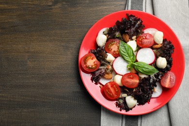 Photo of Delicious vegetable salad with mozzarella served on wooden table, top view. Space for text