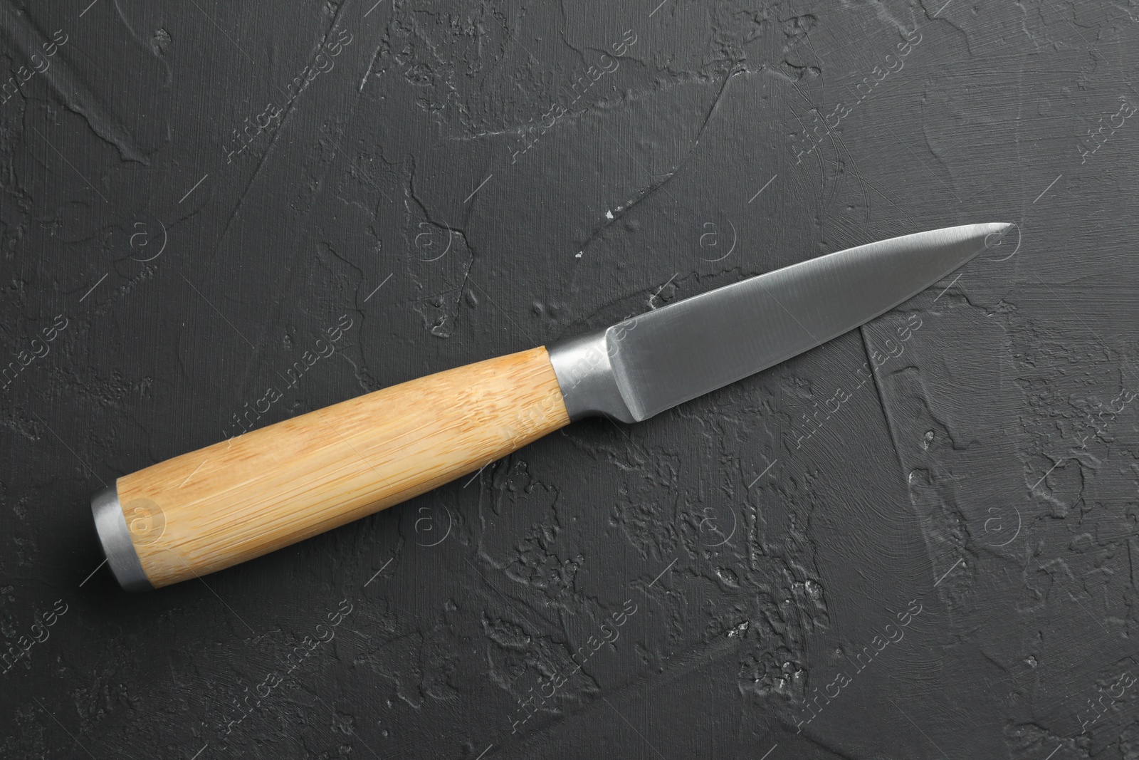 Photo of One sharp knife on dark textured table, top view