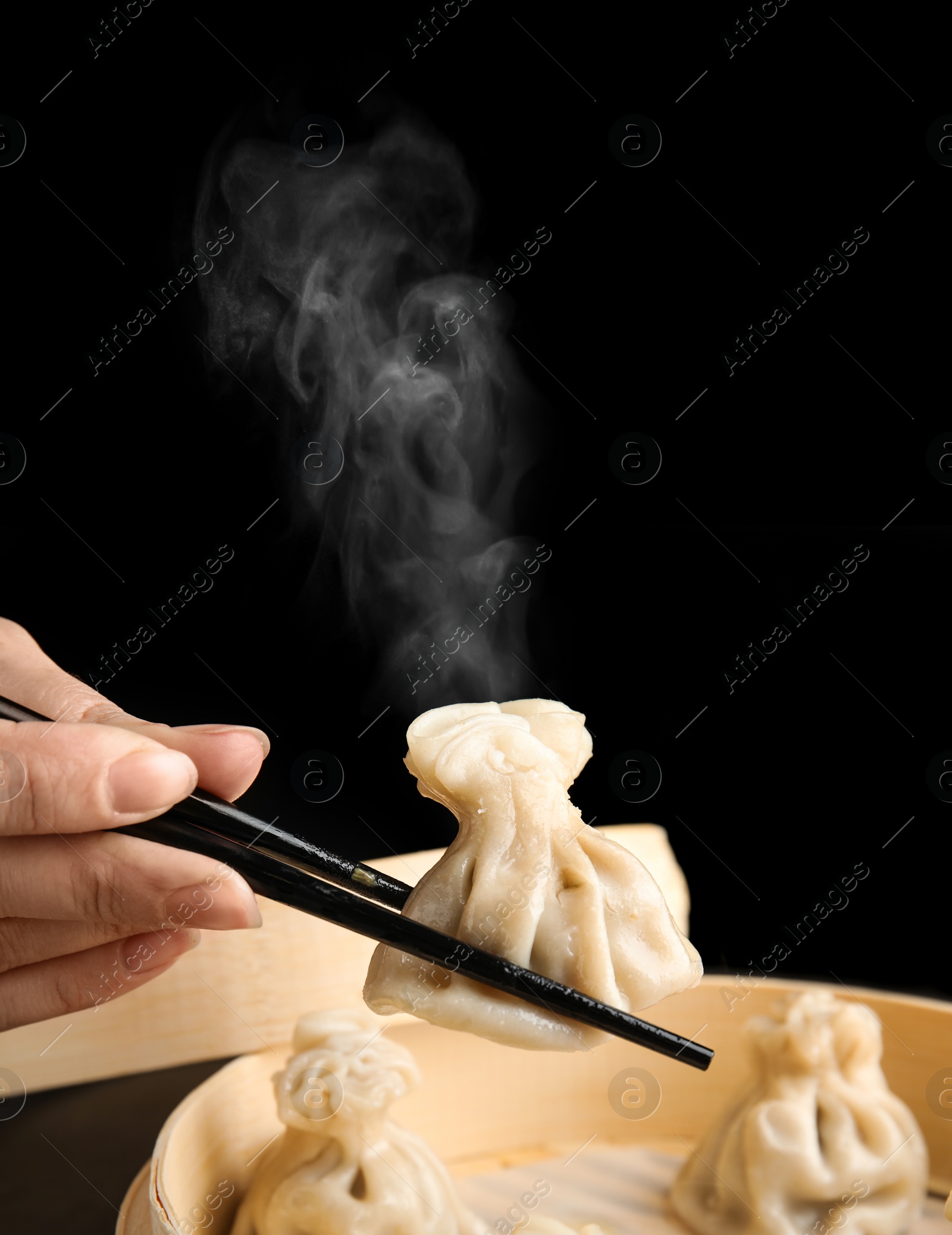 Image of Woman cooking tasty baozi dumplings in bamboo steamer, closeup