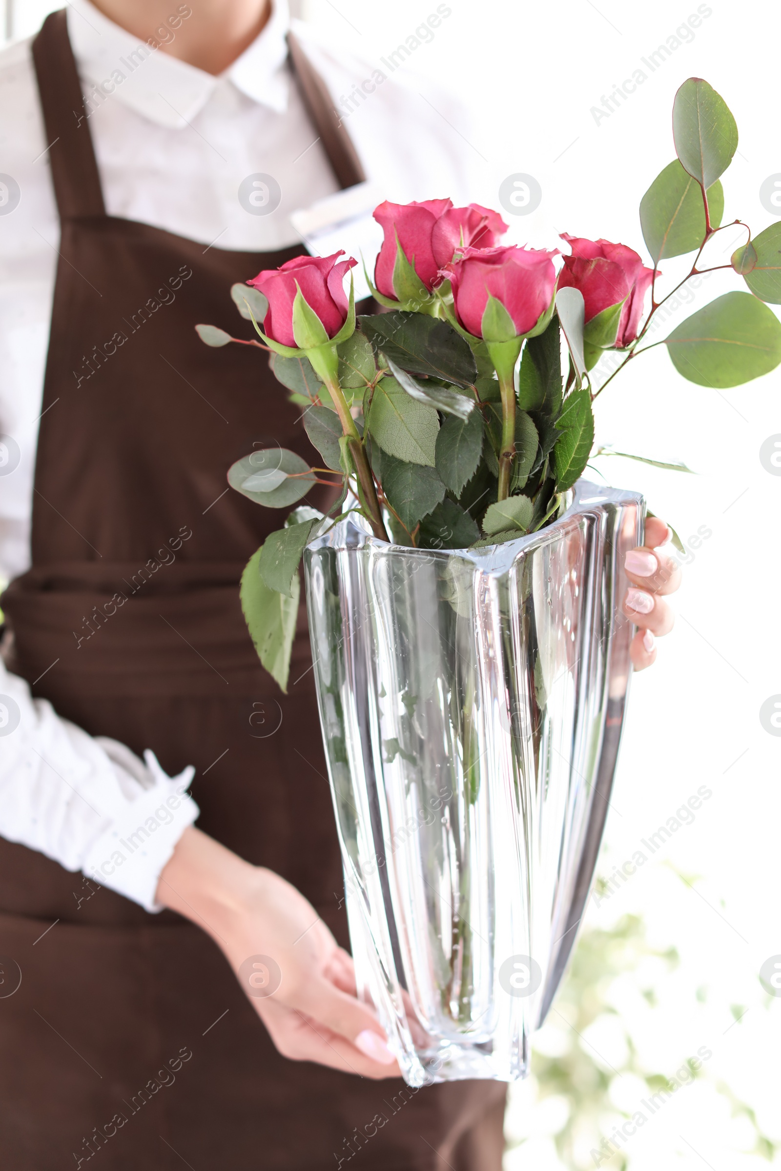 Photo of Female florist holding vase with bouquet in shop