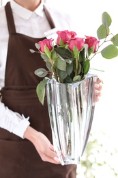 Female florist holding vase with bouquet in shop