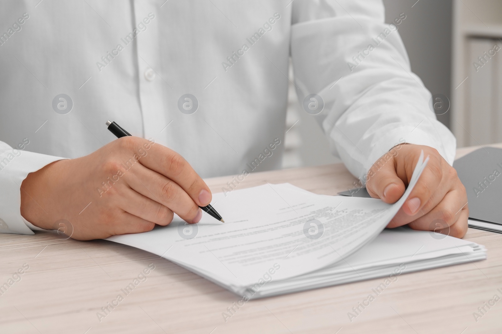 Photo of Man signing document at wooden table, closeup