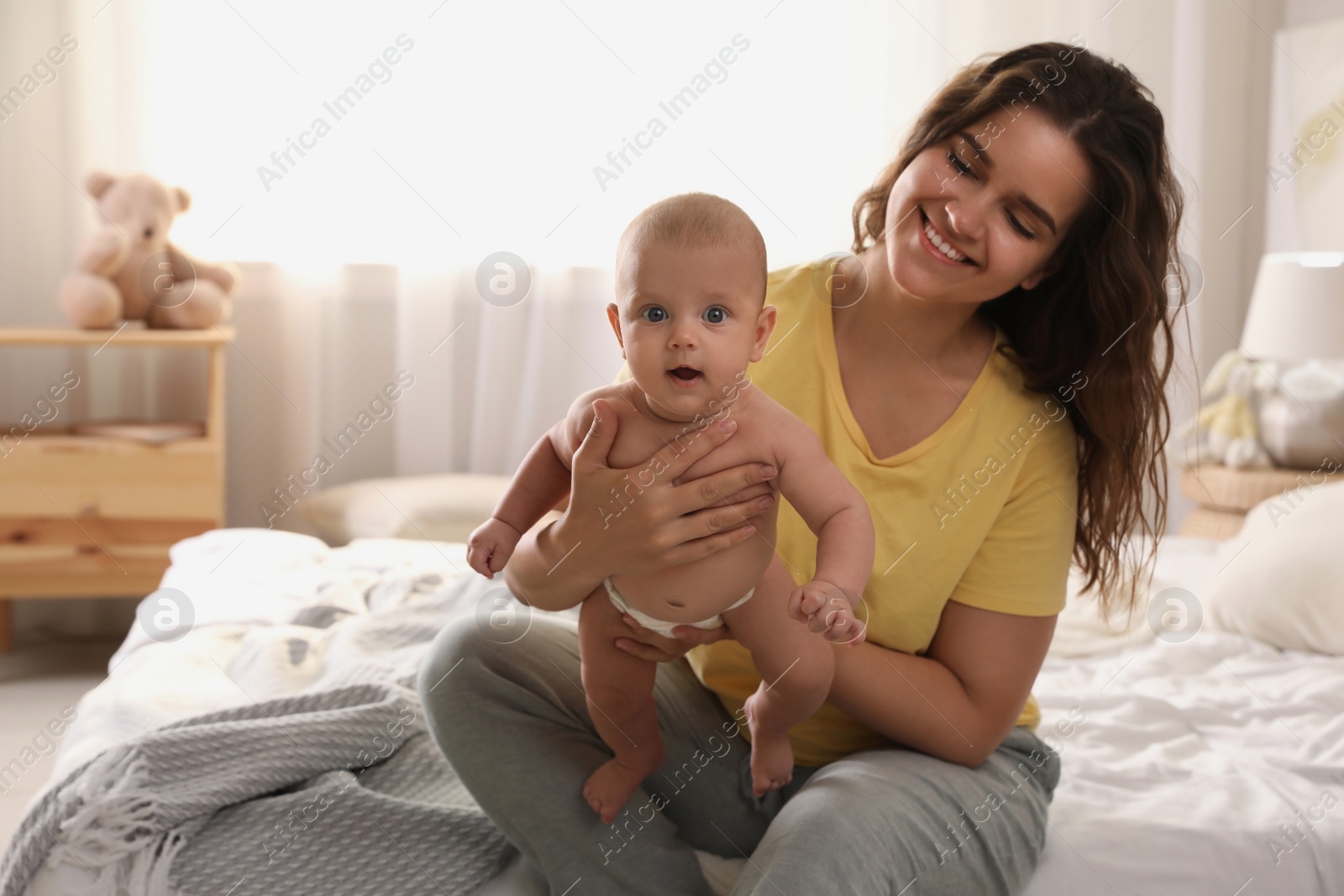 Photo of Happy young mother with her cute baby on bed at home