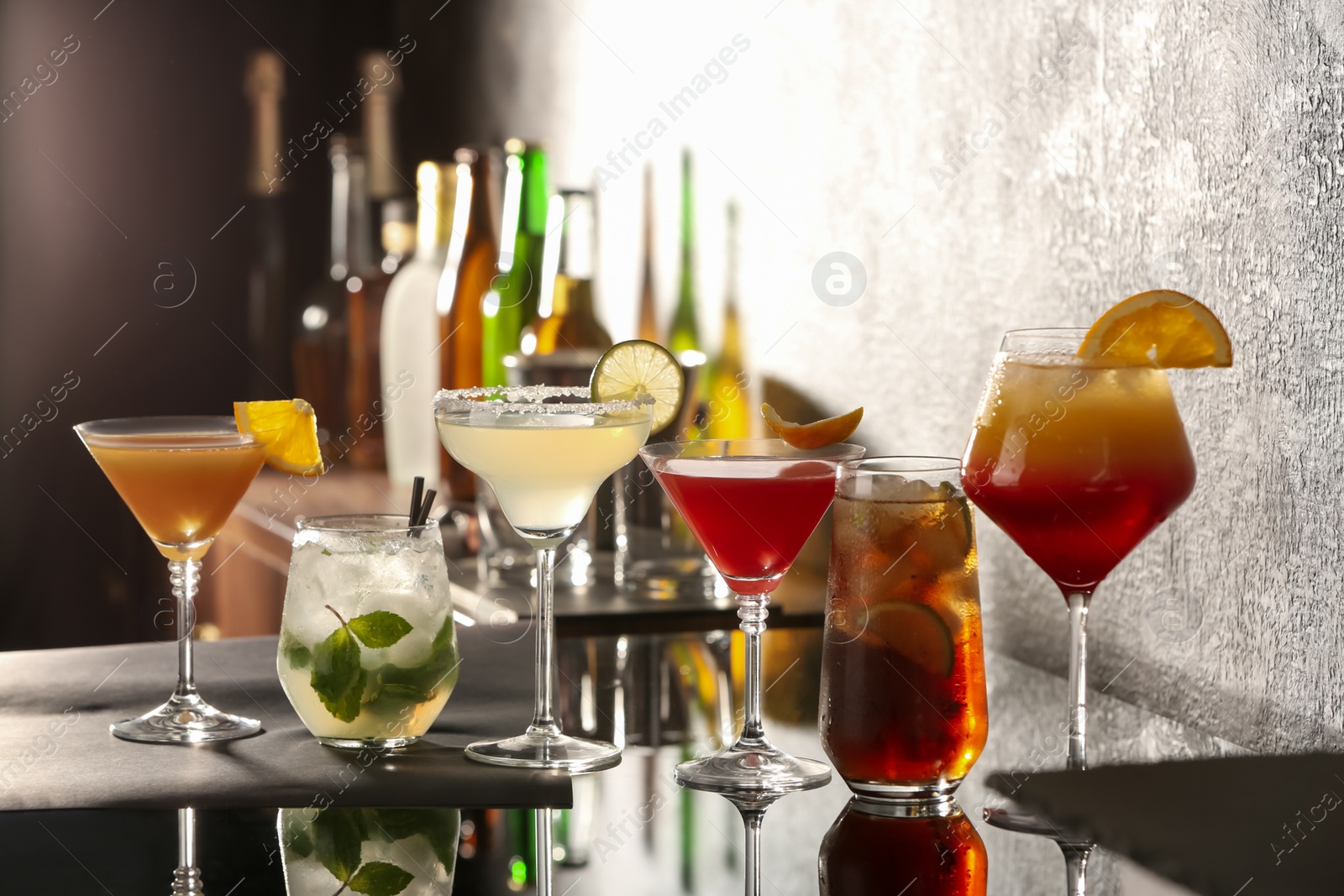 Photo of Different delicious cocktails on black table in bar