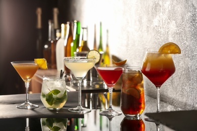 Photo of Different delicious cocktails on black table in bar