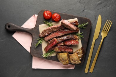 Delicious grilled beef with vegetables and rosemary served on dark gray table, flat lay