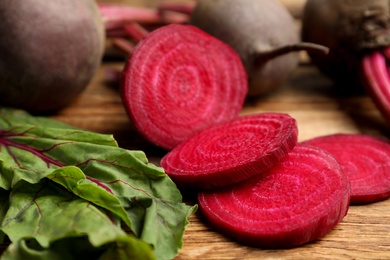 Photo of Cut raw beet on wooden table, closeup