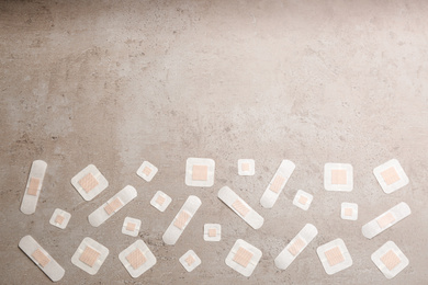 Photo of Different types of sticking plasters on stone background, flat lay. Space for text