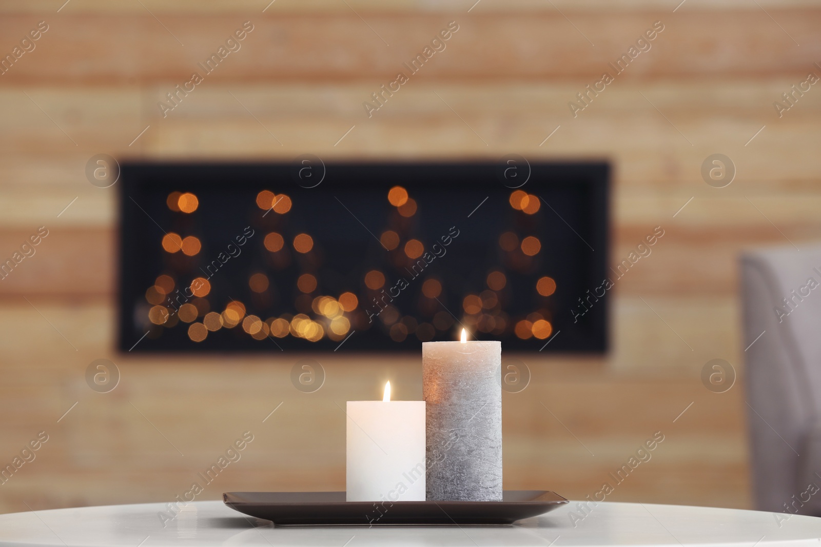 Photo of Plate with burning candles on table against blurred background