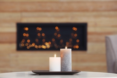 Photo of Plate with burning candles on table against blurred background