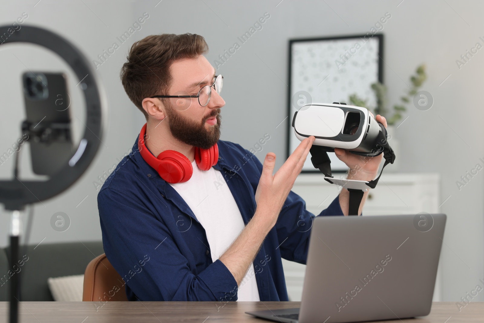 Photo of Technology blogger recording video review about virtual reality headset at home