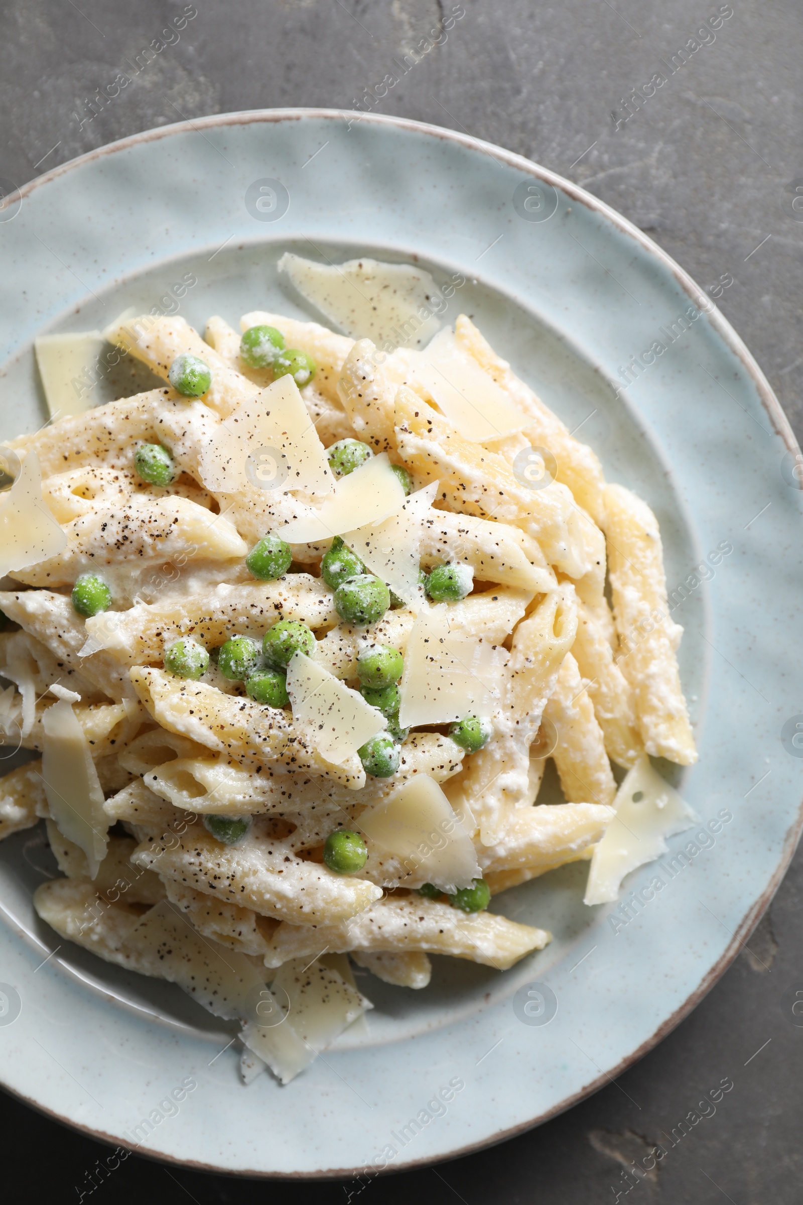 Photo of Delicious pasta with green peas, cheese and creamy sauce on grey table, top view