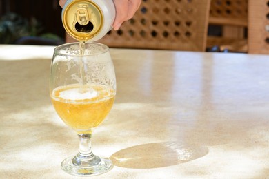 Photo of Man pouring beer from can into glass at table, closeup. Space for text