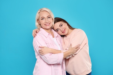 Portrait of mature woman and her daughter on color background