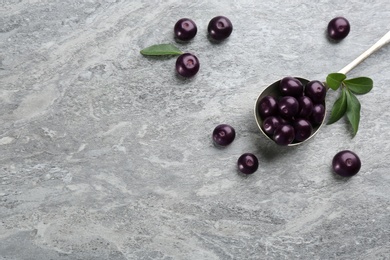 Photo of Fresh acai berries and spoon on light grey table, flat lay. Space for text
