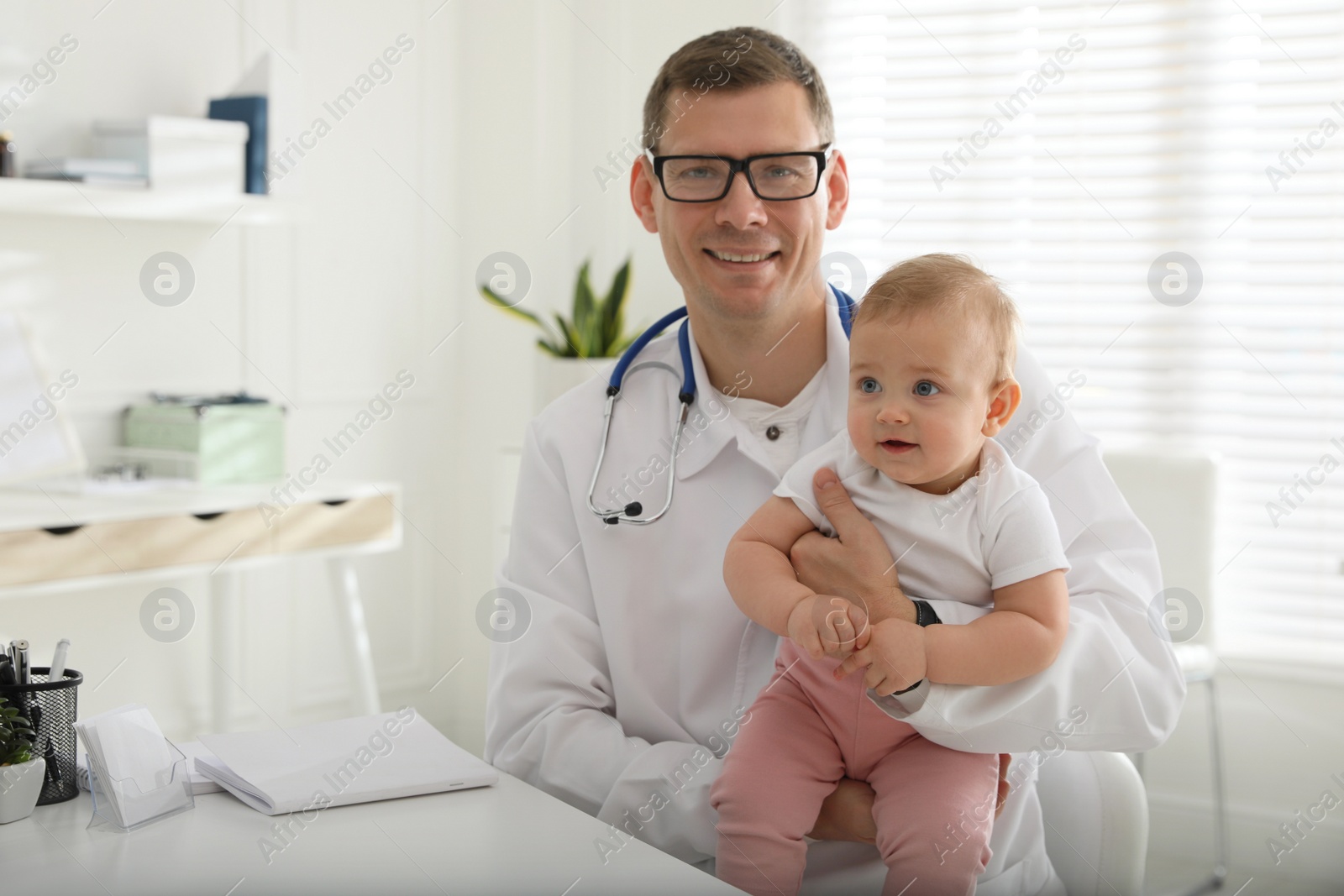 Photo of Pediatrician with cute little baby in clinic
