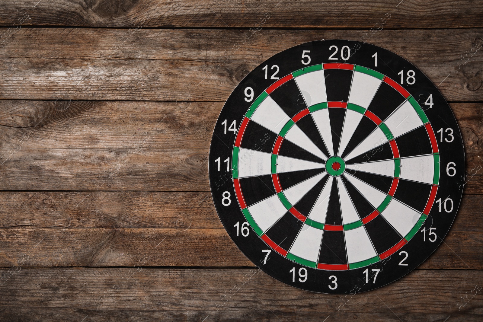 Photo of Dart board on wooden background, top view. Space for text