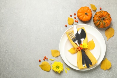 Seasonal table setting with autumn leaves and pumpkins on light grey background, flat lay. Thanksgiving Day