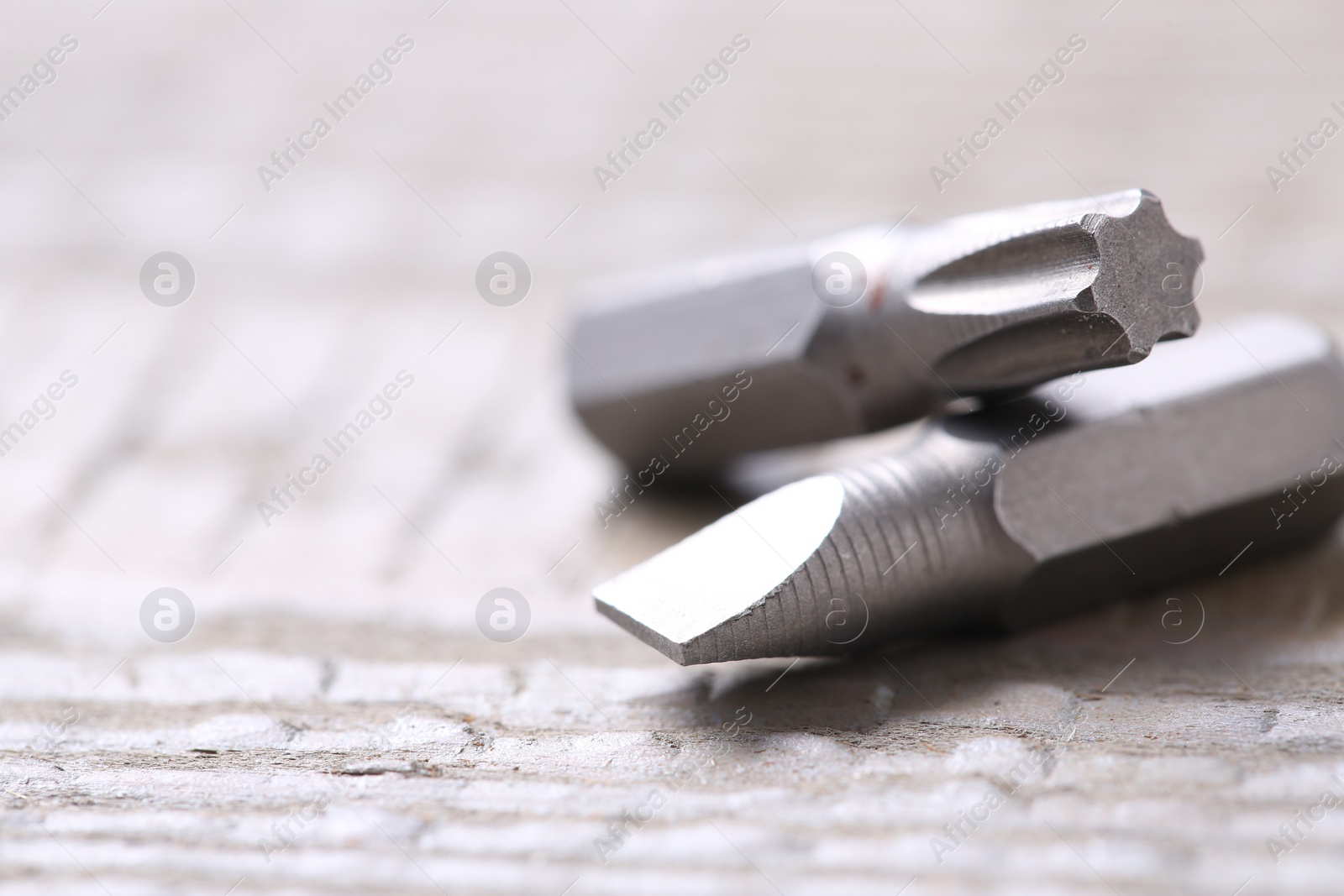 Photo of Different screwdriver bits on wooden table, closeup. Space for text