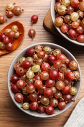Photo of Bowls full of ripe gooseberries on wooden table, above view
