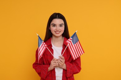 Photo of 4th of July - Independence Day of USA. Happy girl with American flags on yellow background